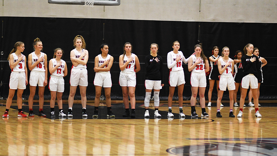 Last years Girls Basketball Team pauses before a game for the National Anthem. This years team is ready to hit the court running and have a successful season.