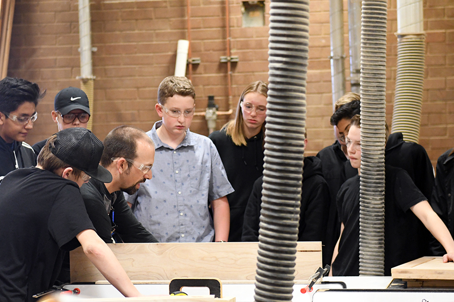 Mr. Joey Newman works with woodworking students. 